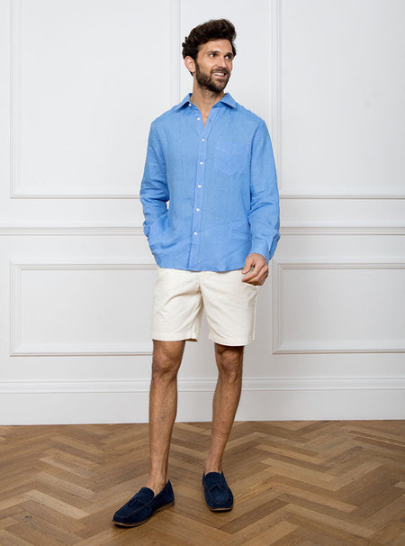Man wearing a sky blue long sleeved shirt with pocket detail made with 100% linen in a Thomas Mason fabric.